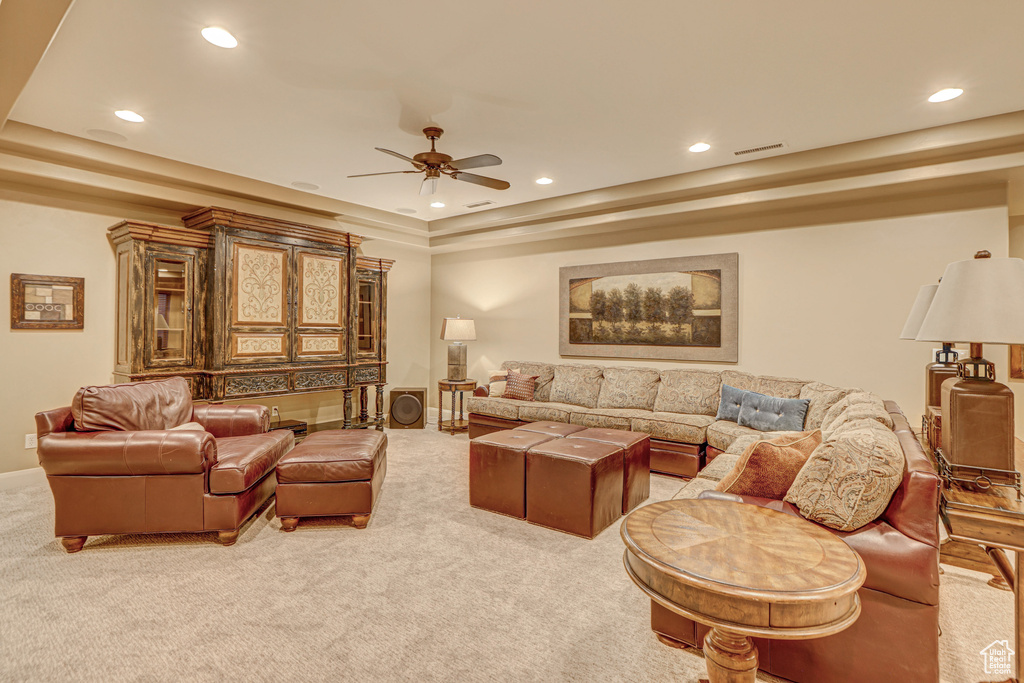 Living room with a tray ceiling, light carpet, and ceiling fan