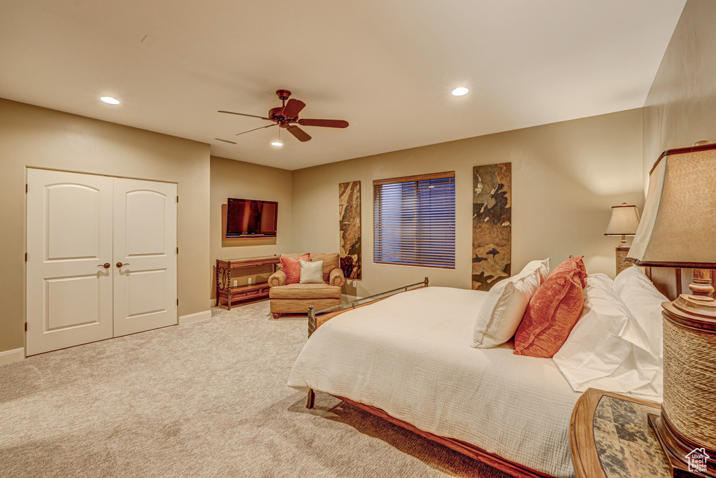 Bedroom with light carpet, ceiling fan, and a closet