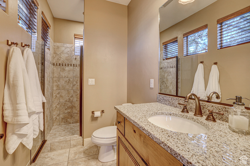 Bathroom featuring tile floors, large vanity, toilet, and tiled shower