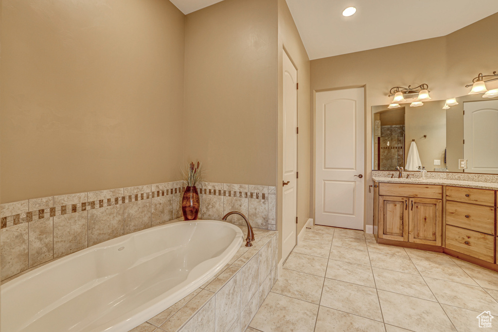 Bathroom featuring vanity, tiled bath, and tile floors