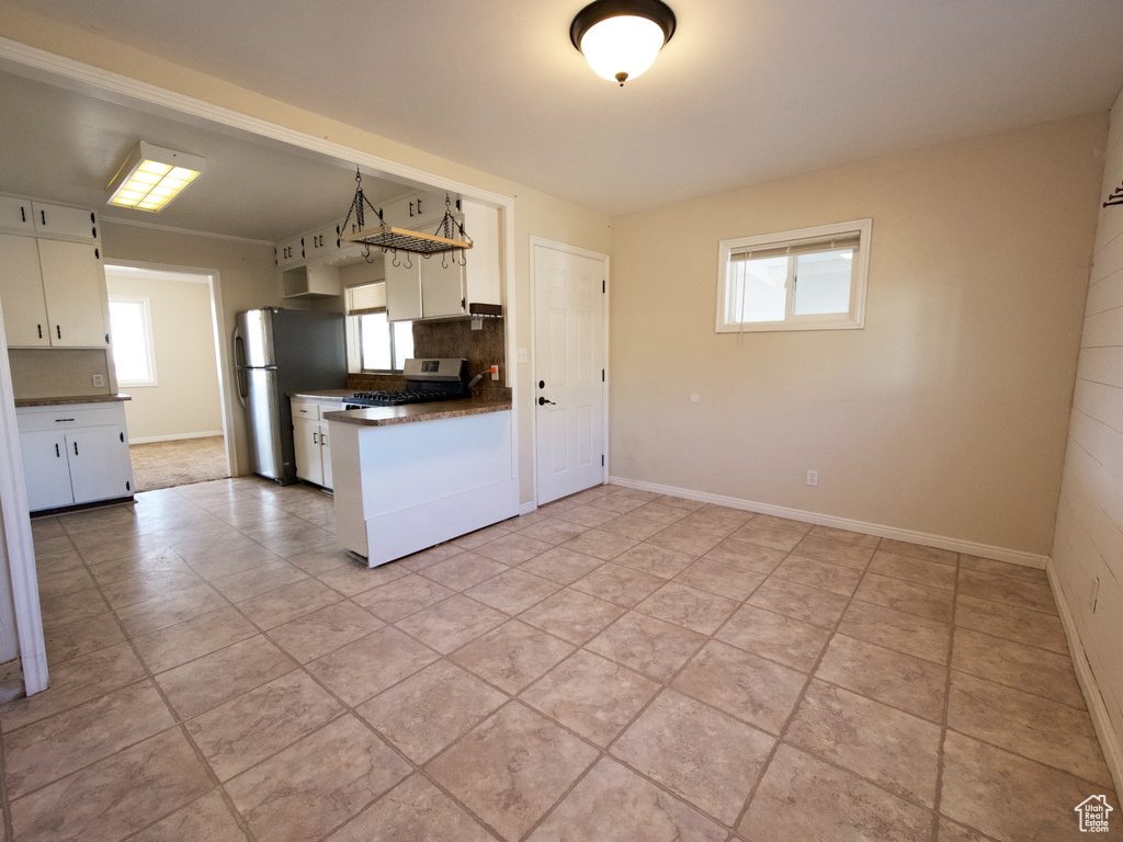 Kitchen featuring white cabinetry, backsplash, light tile flooring, and range