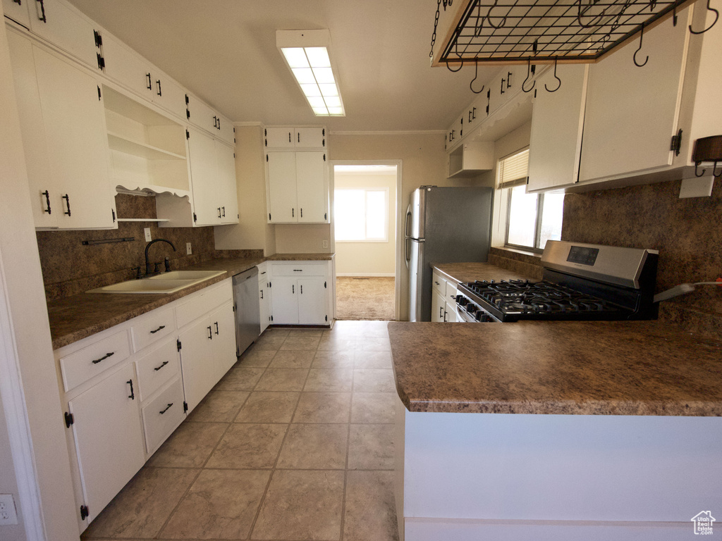 Kitchen featuring backsplash, white cabinets, appliances with stainless steel finishes, light tile floors, and sink