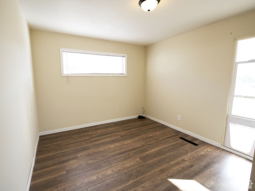 Unfurnished room with dark wood-type flooring and a healthy amount of sunlight