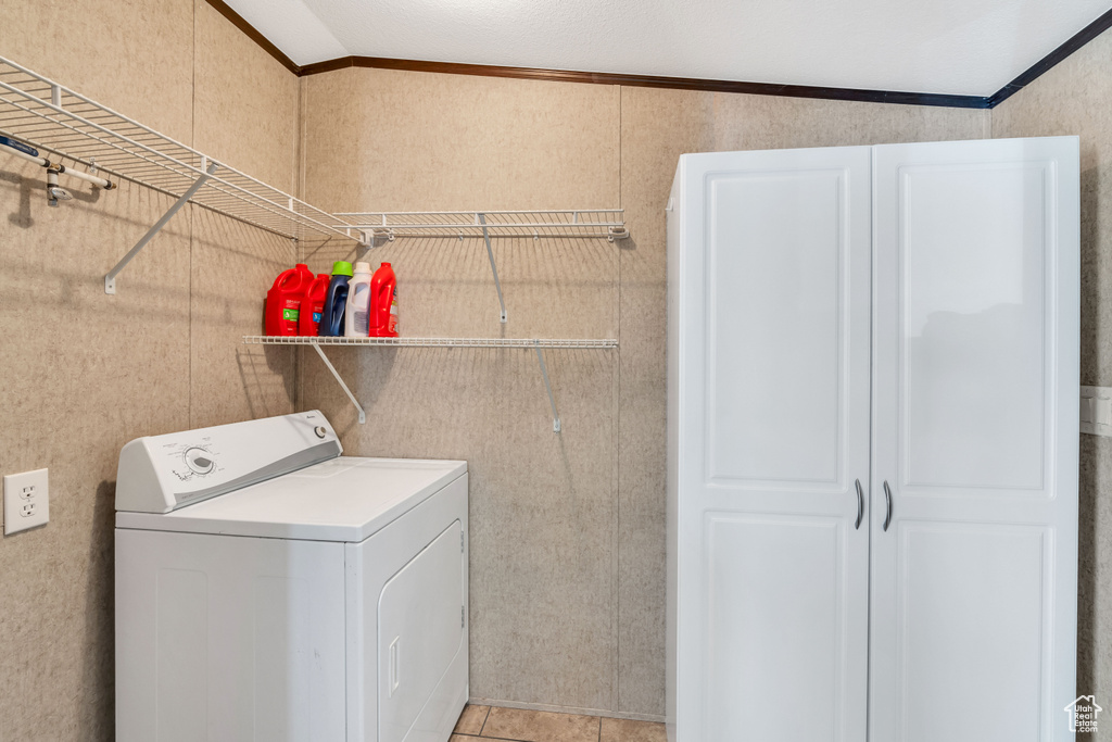 Laundry room featuring washer / clothes dryer, ornamental molding, and light tile floors