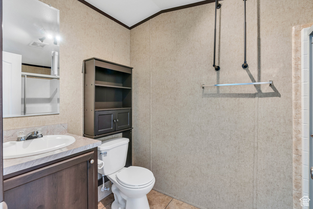 Bathroom with vanity with extensive cabinet space, lofted ceiling, ornamental molding, toilet, and tile flooring