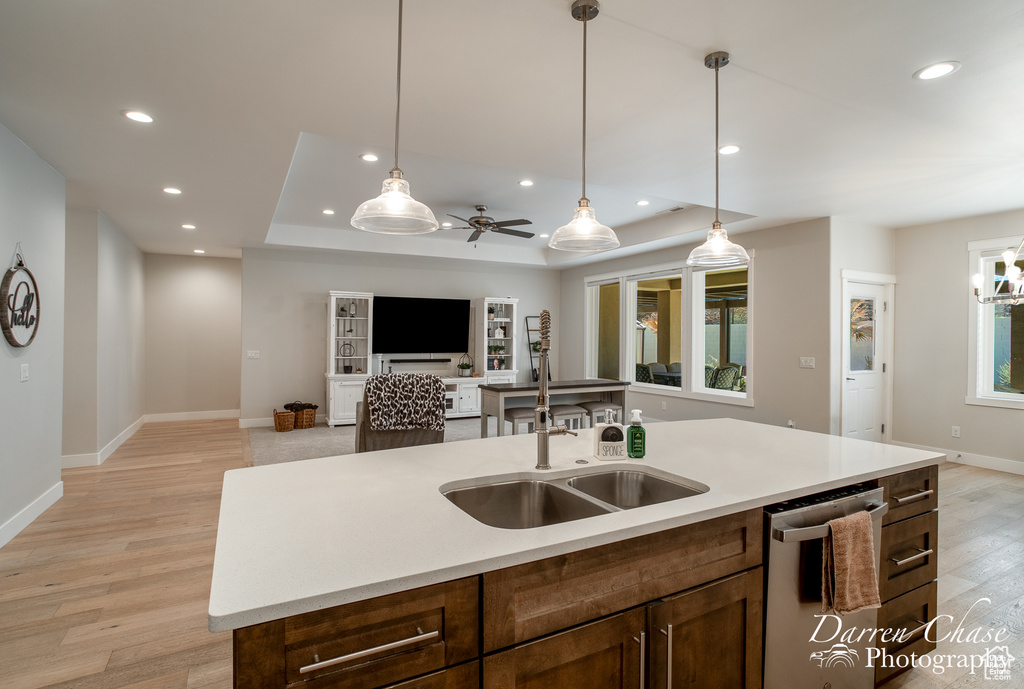 Kitchen with a raised ceiling, pendant lighting, light hardwood / wood-style floors, dishwasher, and ceiling fan