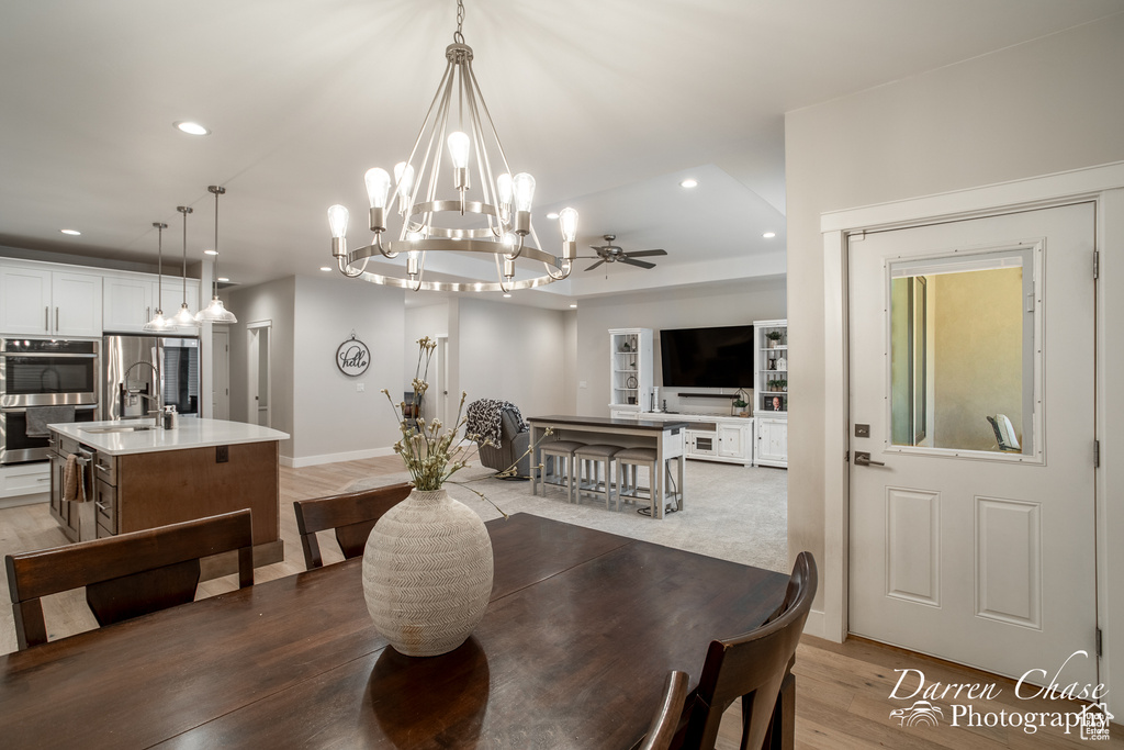 Dining space with ceiling fan with notable chandelier, hardwood / wood-style flooring, and sink
