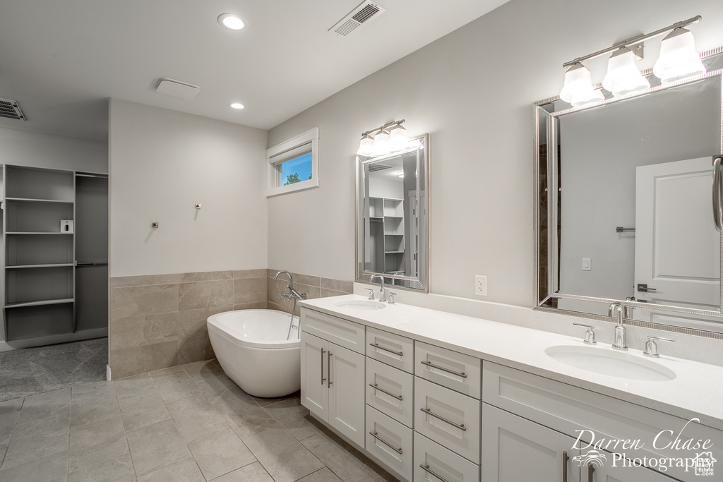 Bathroom with tile floors, double sink vanity, and a bathtub