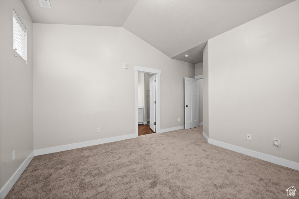 Spare room featuring lofted ceiling and light colored carpet