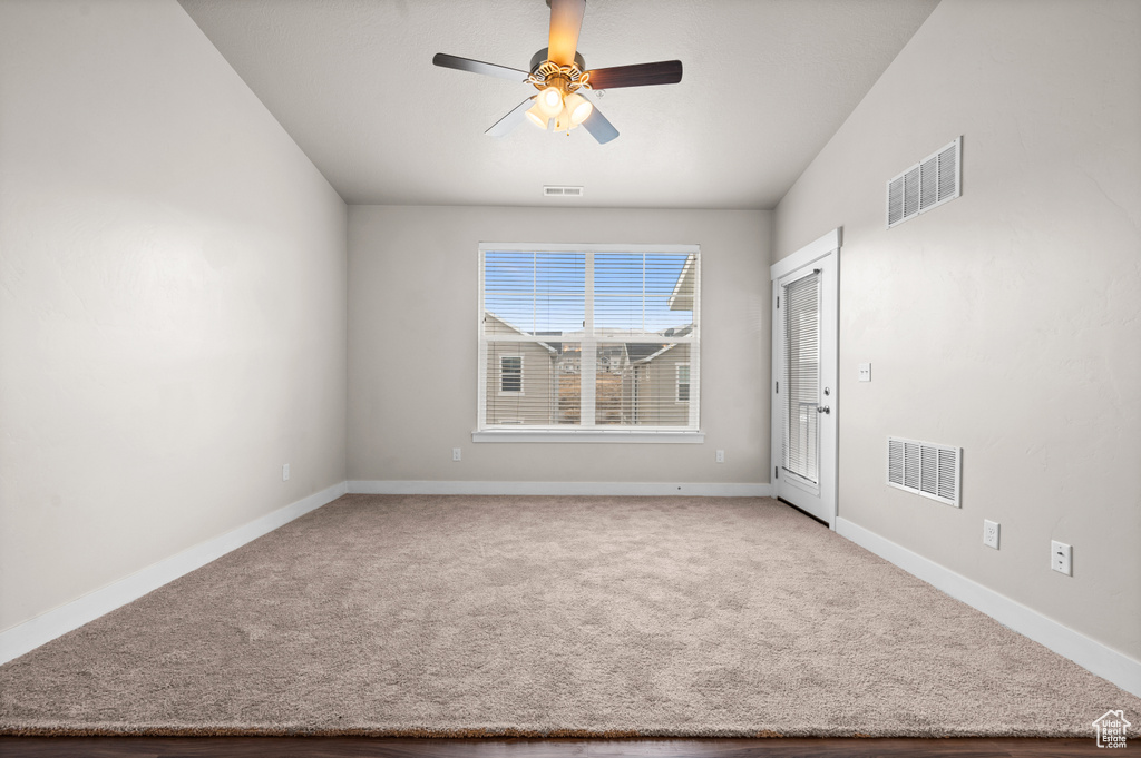 Empty room featuring light carpet, lofted ceiling, and ceiling fan
