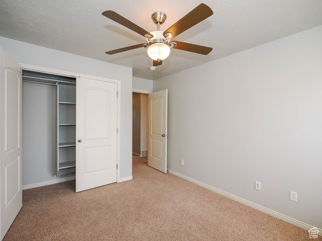 Unfurnished bedroom with light carpet, a closet, and ceiling fan