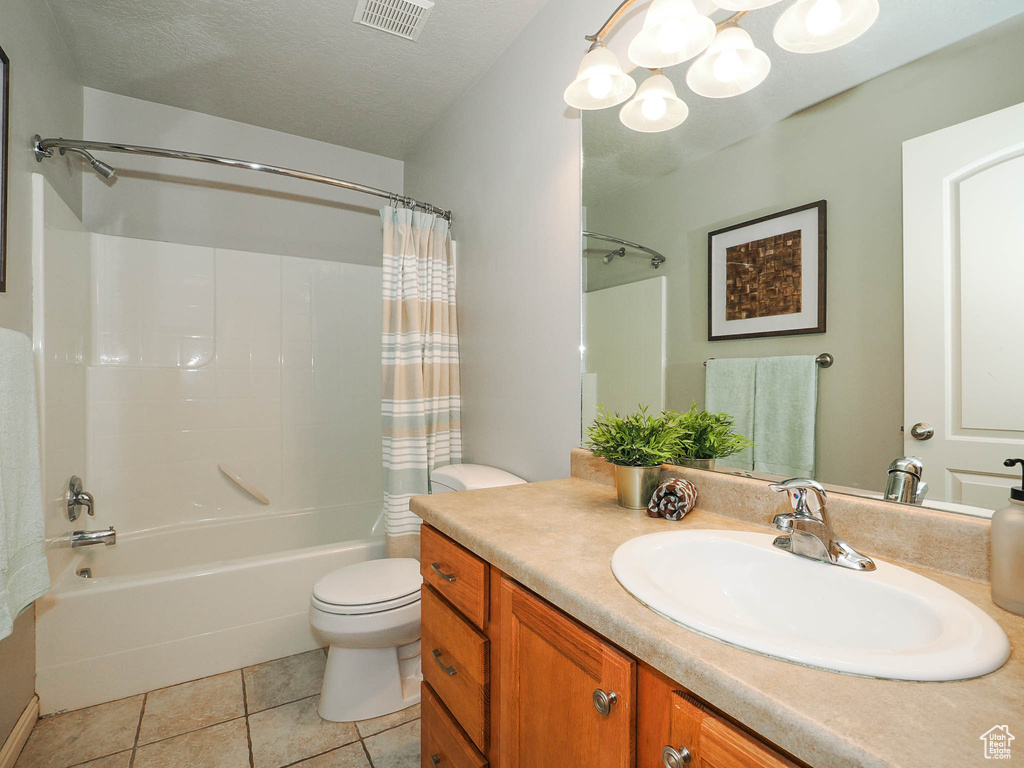 Full bathroom with vanity, a textured ceiling, shower / tub combo, toilet, and tile floors