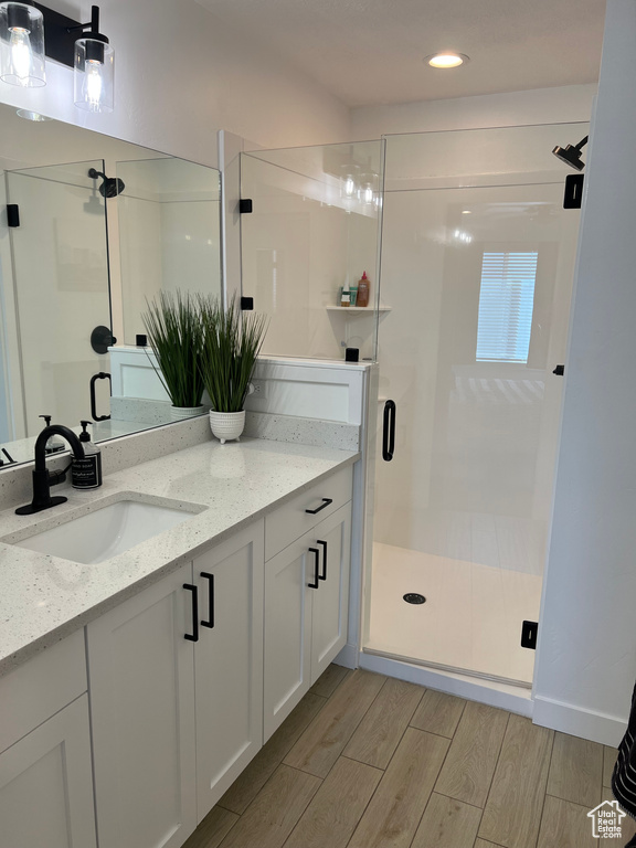 Bathroom featuring hardwood / wood-style floors, vanity, and a shower with shower door