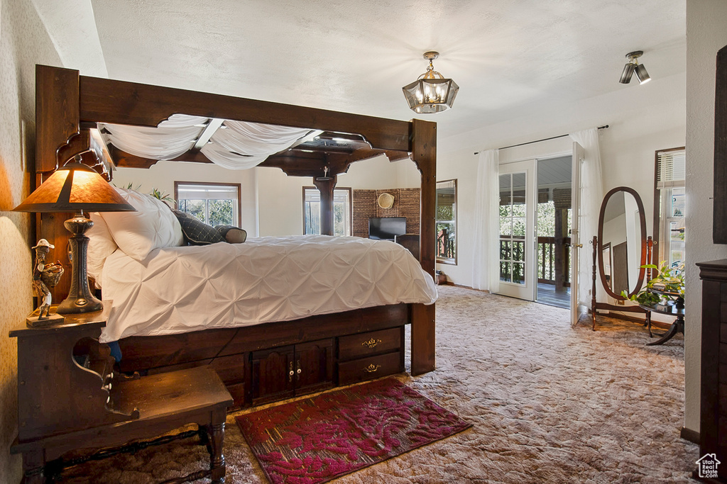 Carpeted bedroom with access to outside and a notable chandelier