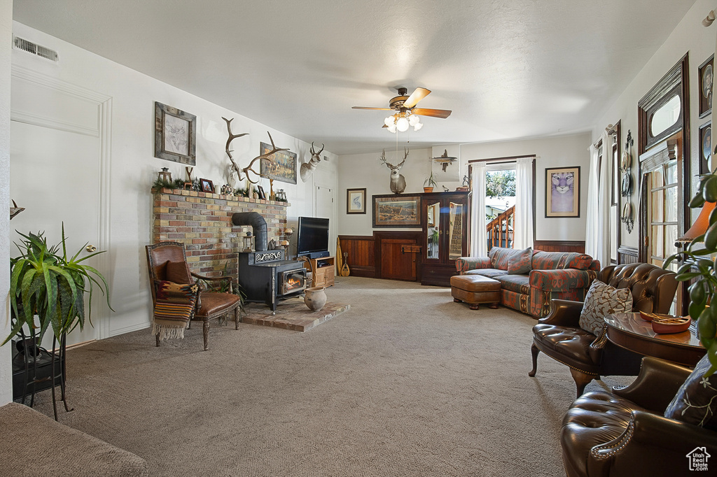 Carpeted living room featuring a wood stove and ceiling fan