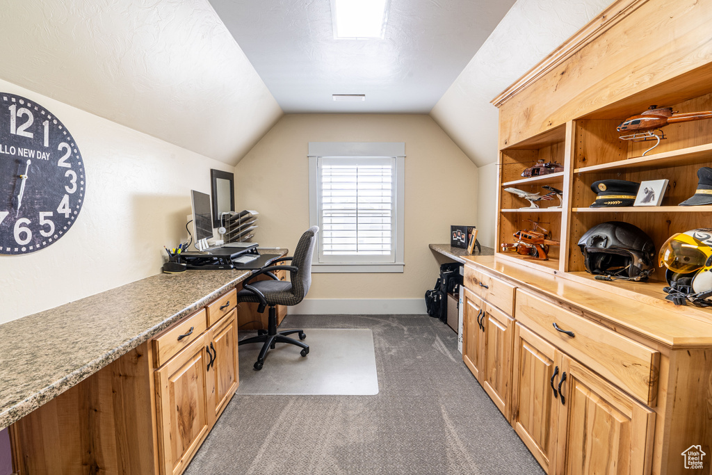 Home office featuring dark colored carpet and vaulted ceiling