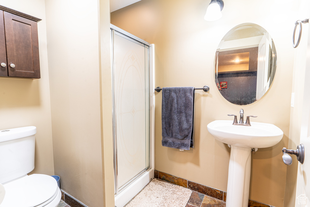 Bathroom with an enclosed shower, tile floors, and toilet