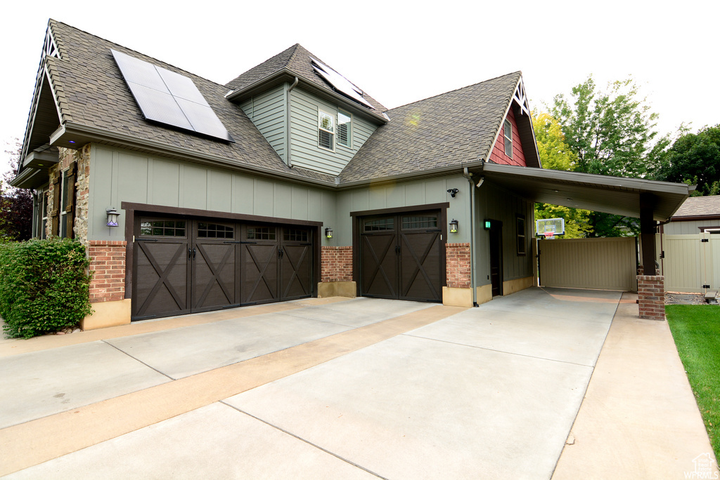 View of front of home featuring solar panels, a garage, and a carport