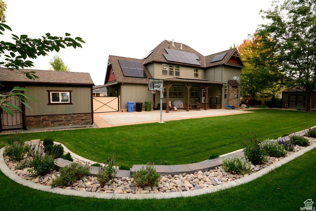Back of property with a lawn, a patio, and solar panels