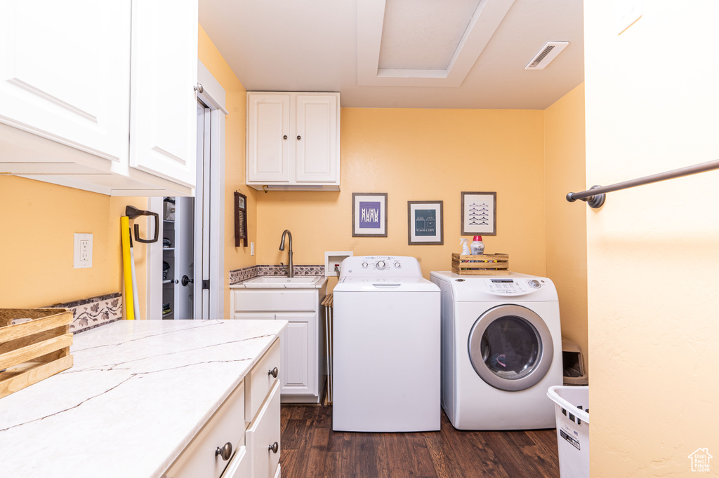 Clothes washing area with sink, washer and clothes dryer, dark hardwood / wood-style floors, washer hookup, and cabinets