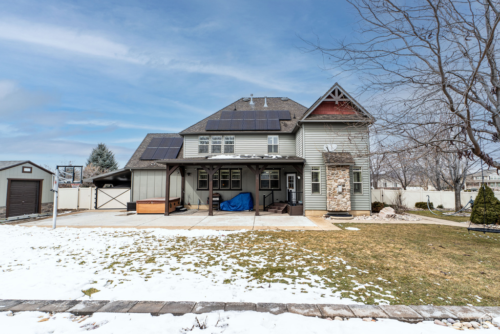 View of front of property featuring a patio area, solar panels, and a lawn