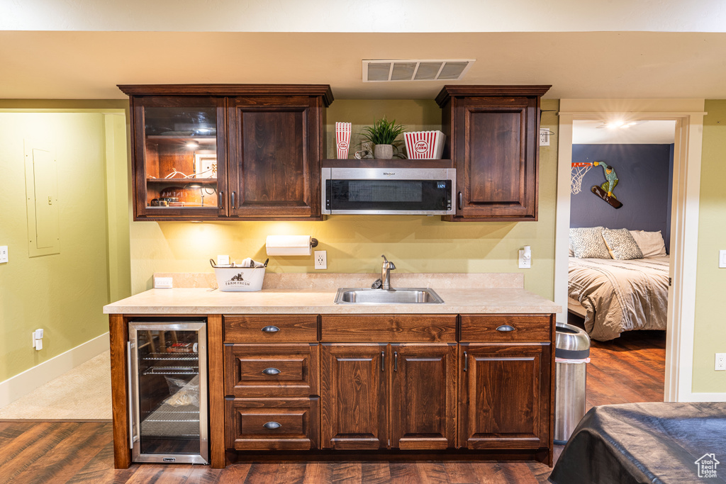 Kitchen with wine cooler, dark hardwood / wood-style flooring, sink, and dark brown cabinetry