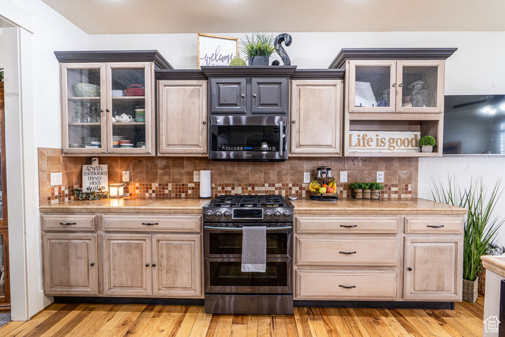 Kitchen featuring light hardwood / wood-style flooring, tasteful backsplash, and range with two ovens