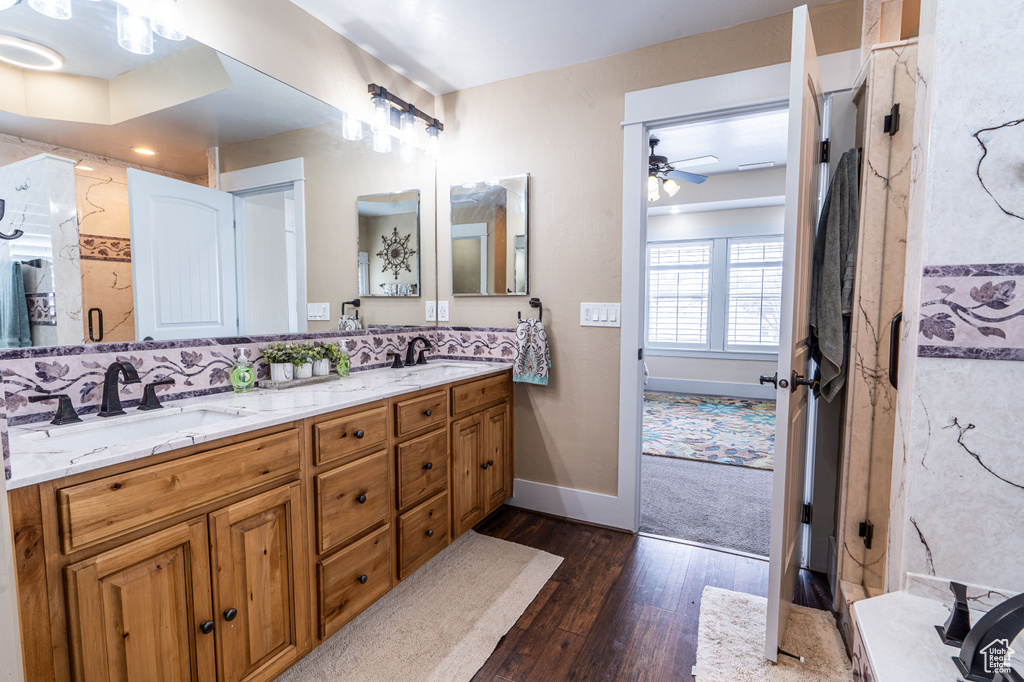 Bathroom with dual sinks, ceiling fan, hardwood / wood-style floors, oversized vanity, and a shower