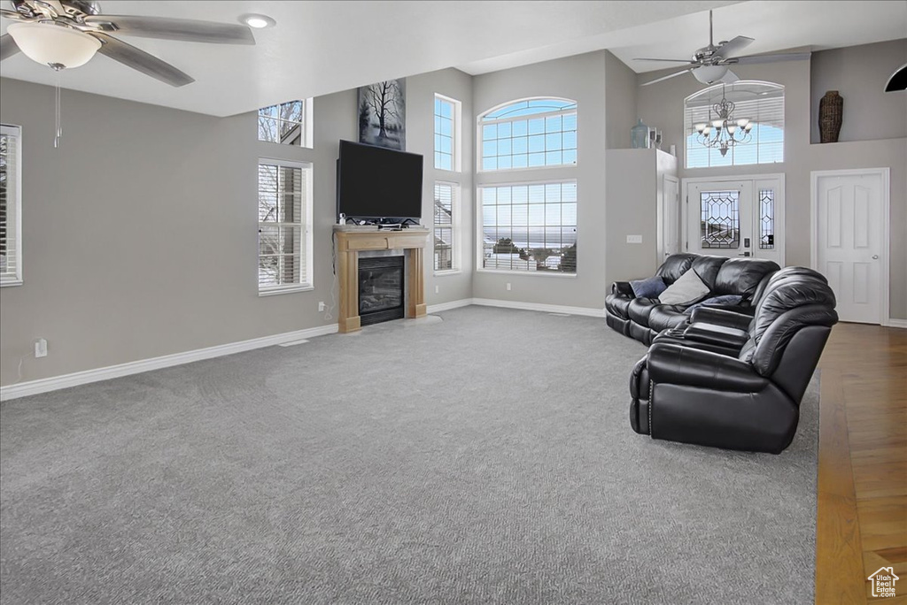 Carpeted living room with a high ceiling and ceiling fan with notable chandelier