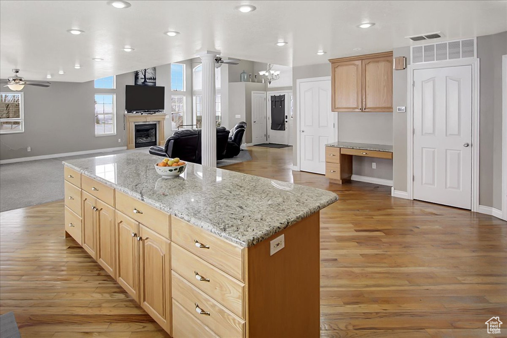 Kitchen featuring light wood-type flooring, a center island, light stone countertops, and ceiling fan