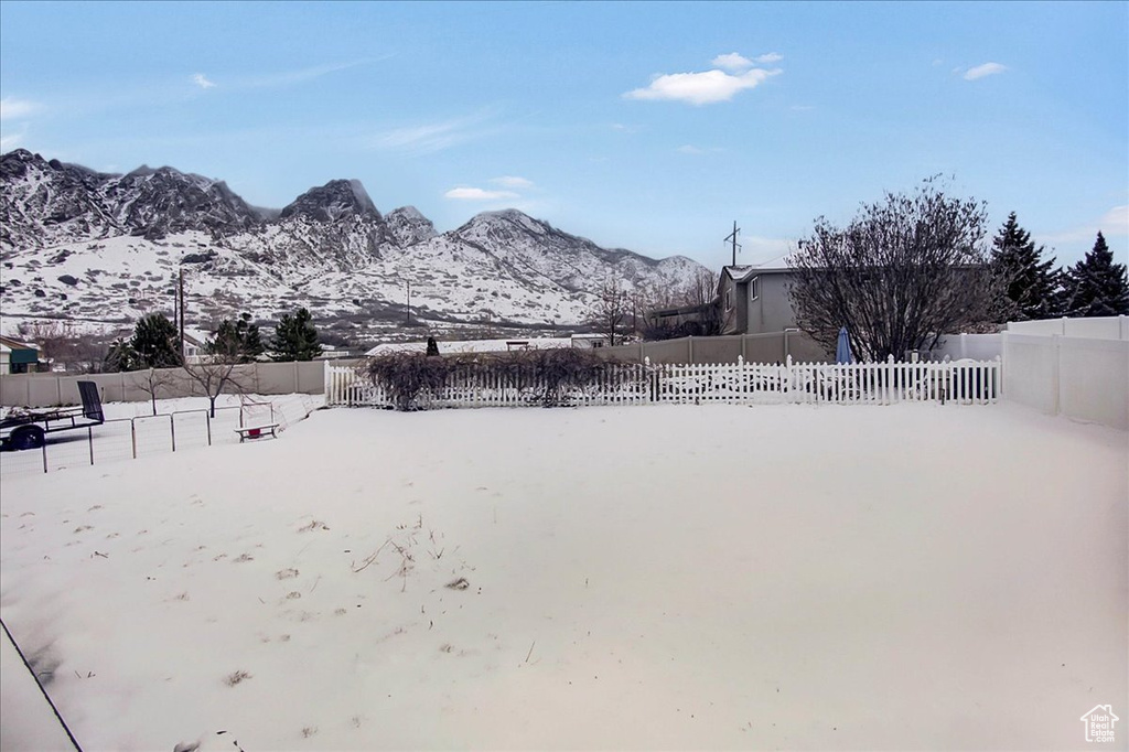 Yard covered in snow featuring a mountain view