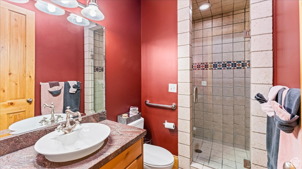 Bathroom with toilet, vanity with extensive cabinet space, and walk in shower