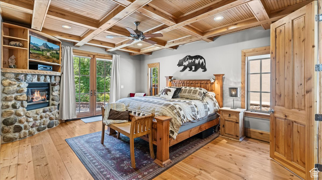 Bedroom featuring coffered ceiling, access to exterior, light hardwood / wood-style flooring, and a fireplace