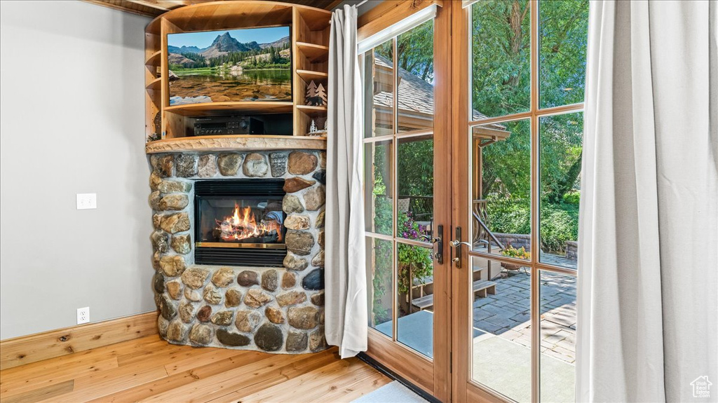 Doorway to outside featuring french doors, a stone fireplace, and hardwood / wood-style floors