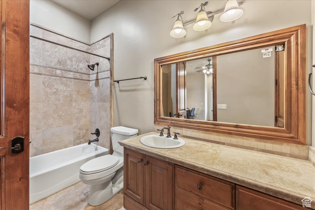 Full bathroom featuring tiled shower / bath, ceiling fan, vanity with extensive cabinet space, toilet, and tile flooring