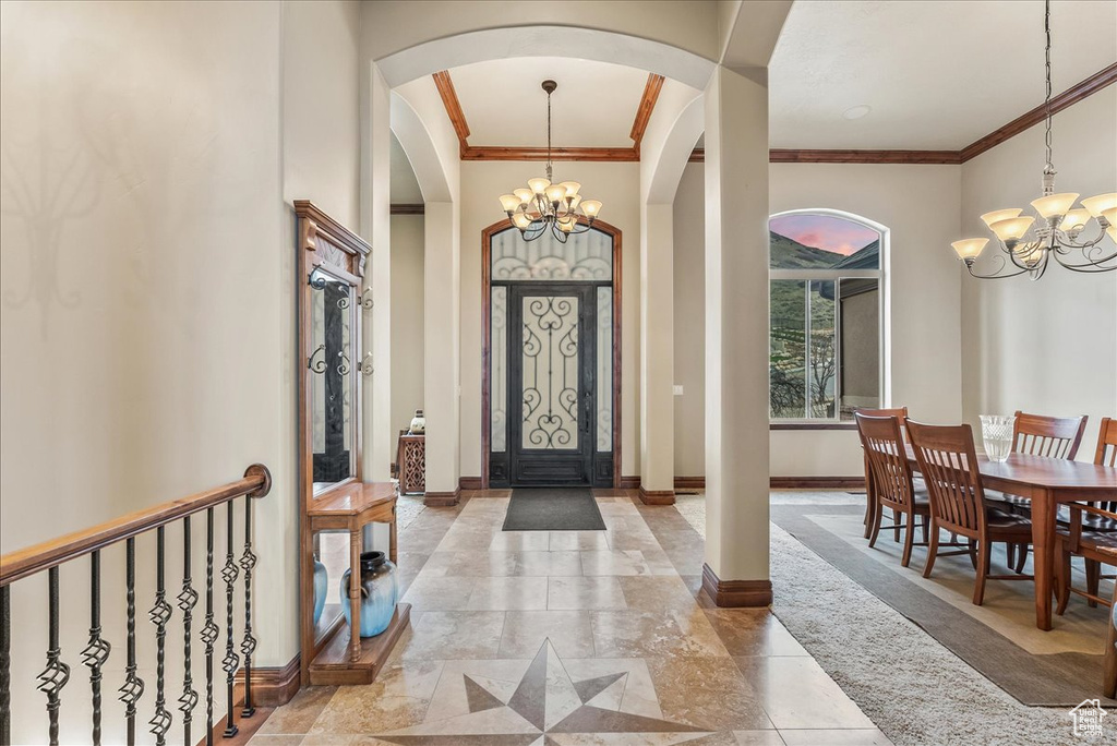 Entrance foyer with an inviting chandelier, ornamental molding, and light tile flooring