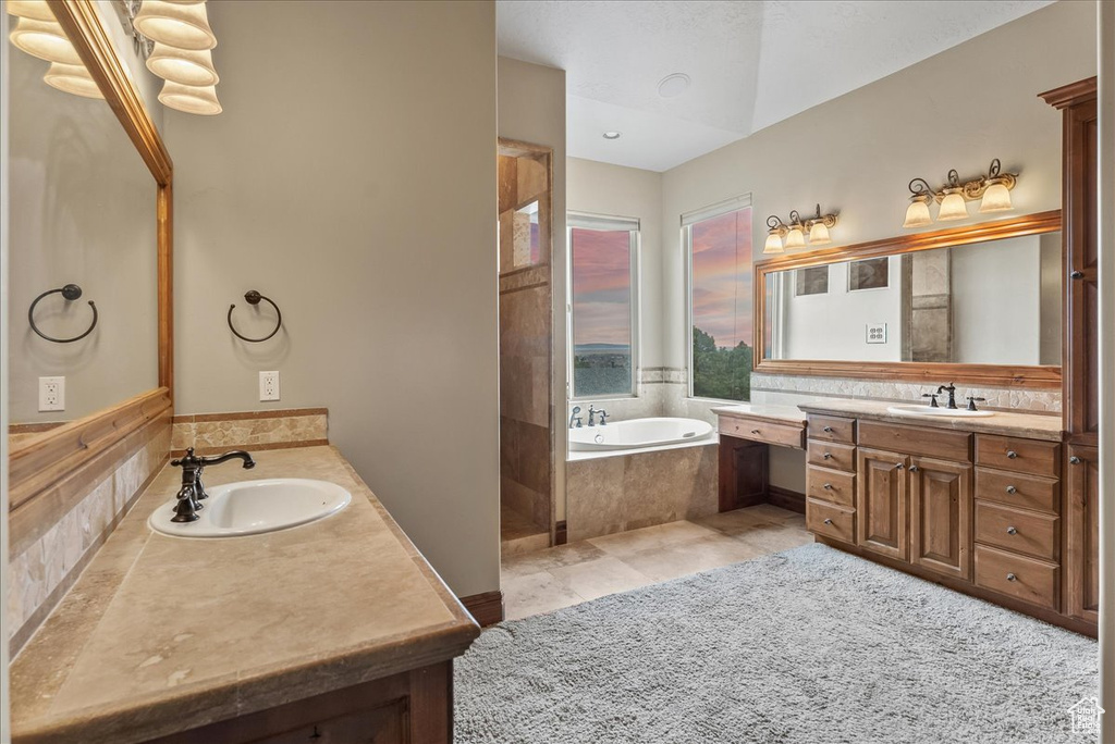 Bathroom with tiled bath, tile floors, and vanity
