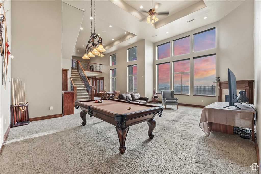 Rec room featuring pool table, light colored carpet, a tray ceiling, and a towering ceiling