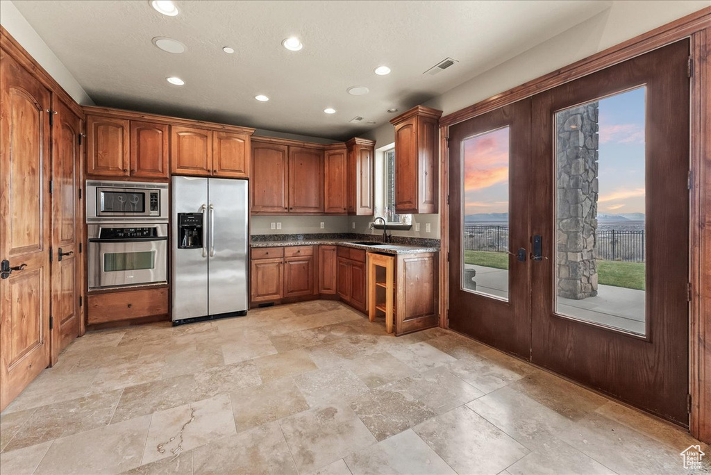 Kitchen featuring stainless steel appliances, light tile flooring, and a healthy amount of sunlight