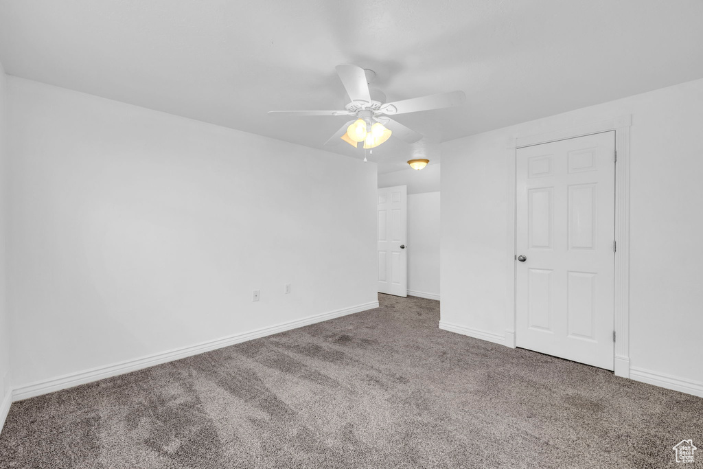 Spare room featuring dark carpet and ceiling fan
