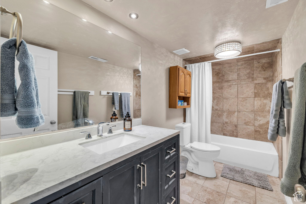 Full bathroom featuring toilet, vanity with extensive cabinet space, tile floors, and shower / bath combination with curtain