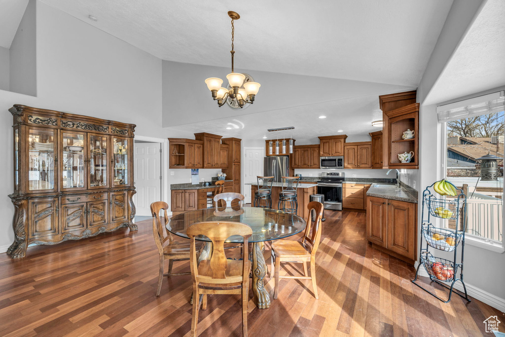 Dining room featuring an inviting chandelier, dark hardwood / wood-style floors, sink, and high vaulted ceiling