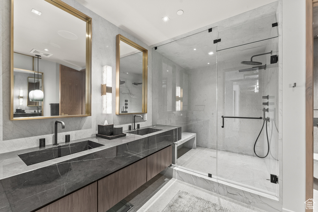Bathroom featuring an enclosed shower, tile walls, tile floors, backsplash, and double vanity