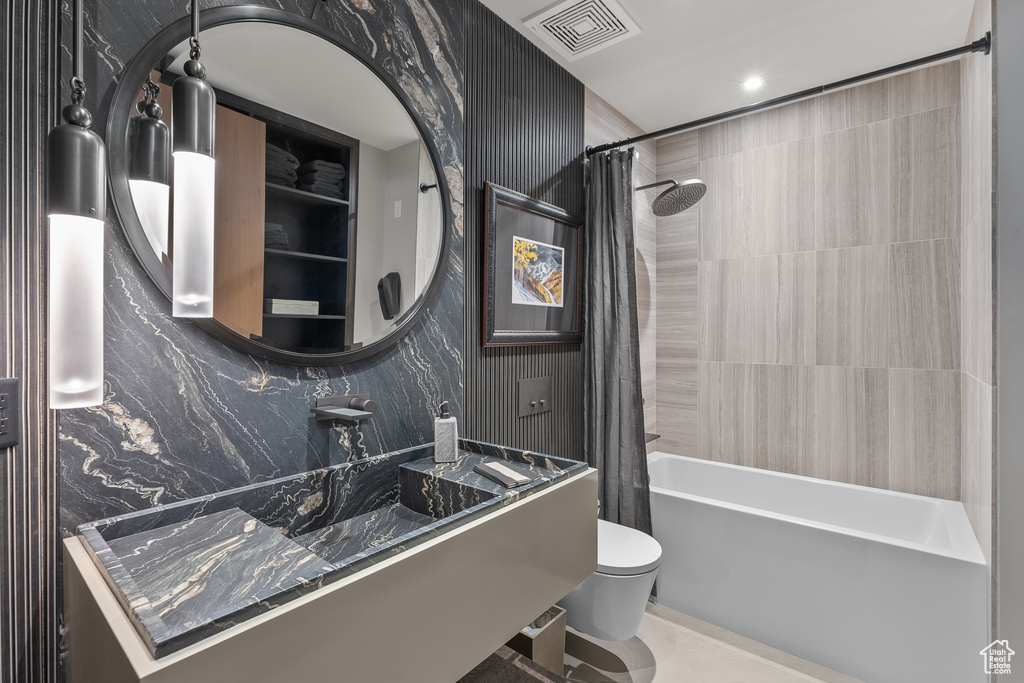 Bathroom with shower / bathtub combination with curtain, tile floors, and toilet