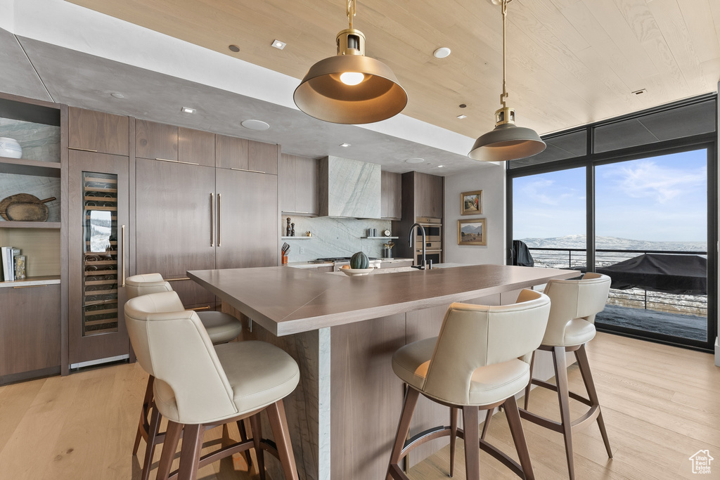 Kitchen with hanging light fixtures, a breakfast bar area, tasteful backsplash, and light hardwood / wood-style floors