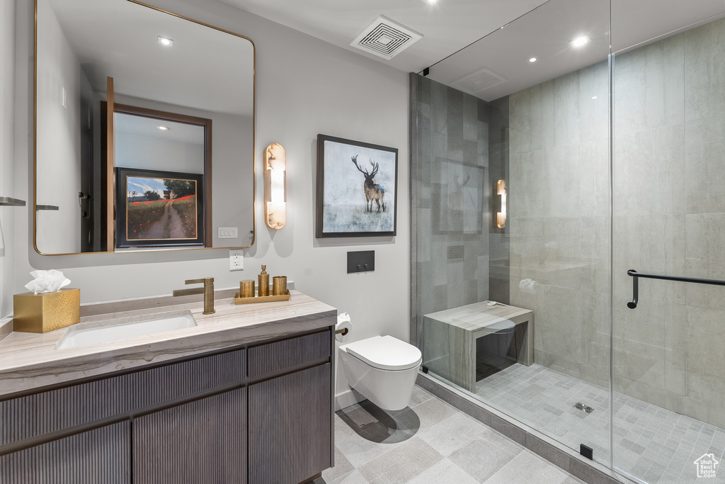 Bathroom featuring vanity, toilet, tile flooring, and a shower with shower door