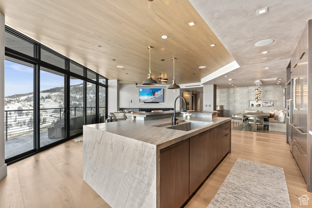 Kitchen featuring sink, a spacious island, light hardwood / wood-style floors, hanging light fixtures, and floor to ceiling windows