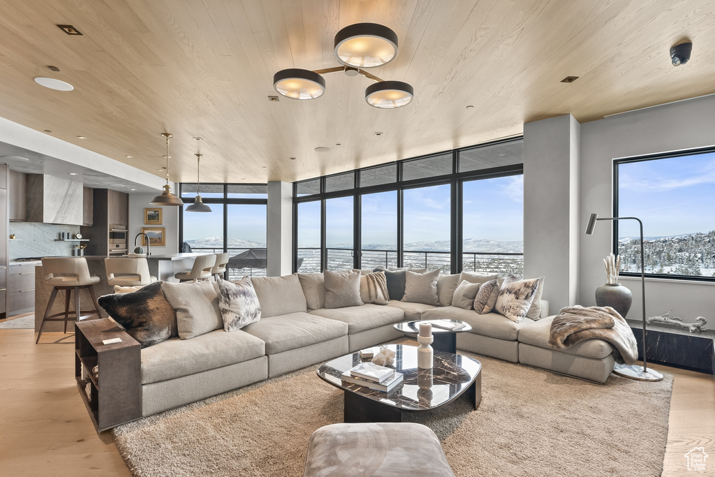Living room with a water view, sink, floor to ceiling windows, wooden ceiling, and light hardwood / wood-style flooring