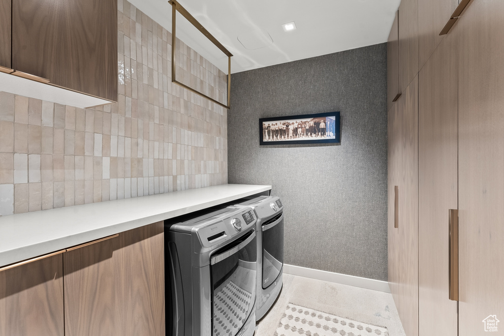 Washroom with cabinets, washer and clothes dryer, and light tile floors