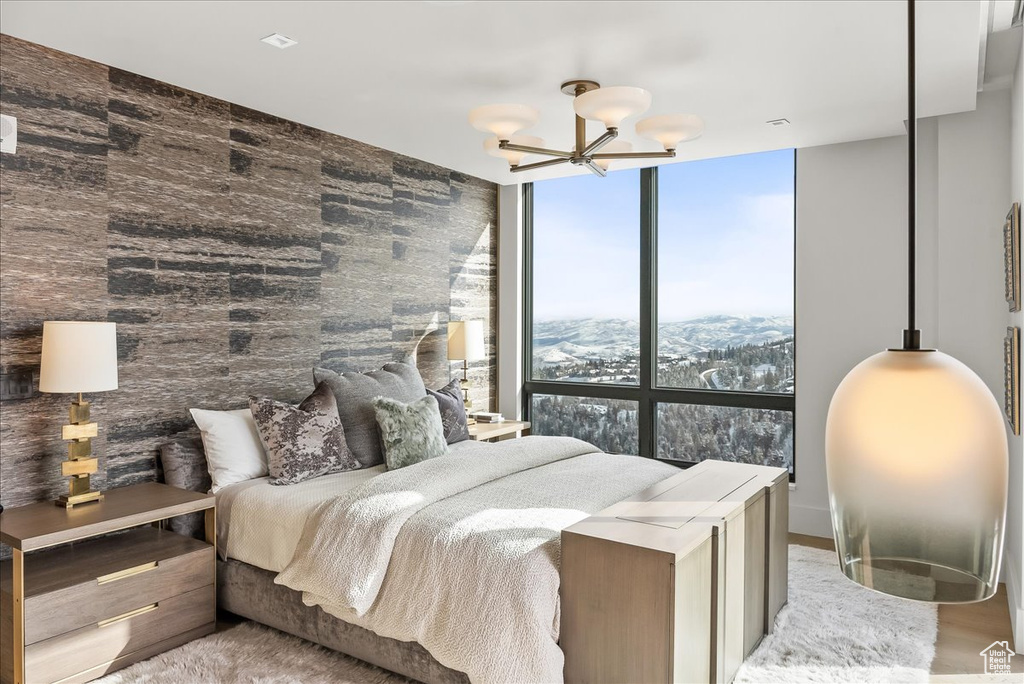 Bedroom featuring a notable chandelier, floor to ceiling windows, and a mountain view